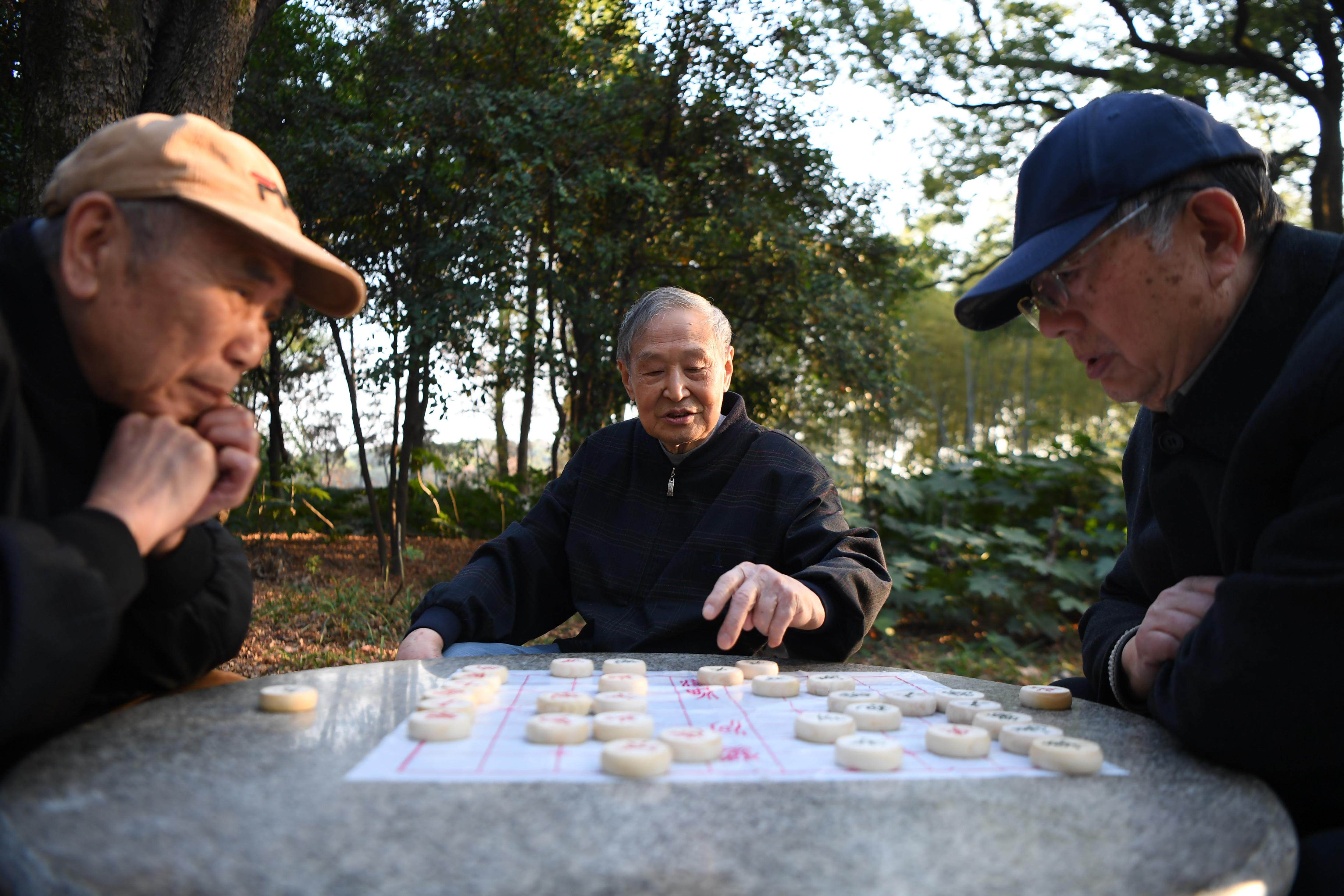 馬利民(左),魏鎮(右)在公園裡下象棋,餘國基在一旁觀戰